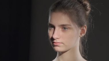 Stüdyoda sakince kameraya bakan kahverengi saçlı genç kızın portresini kapat..