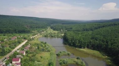 Göl kenarındaki güzel küçük bir köyün ve yeşil ormanın havadan görünüşü. Stok görüntüleri. Modern evlerin, köylerin manzarası..