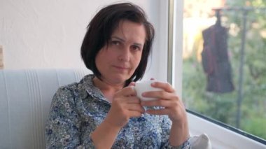 Mutlu kadın evde bir fincan sıcak çay ya da kahveyle dinleniyor.