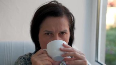 Mutlu kadın evde bir fincan sıcak çay ya da kahveyle dinleniyor.