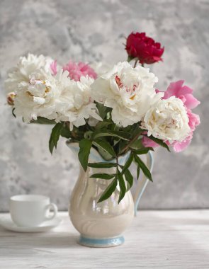 Beyaz ve pembe şakayıkların olduğu beyaz bir vazoda