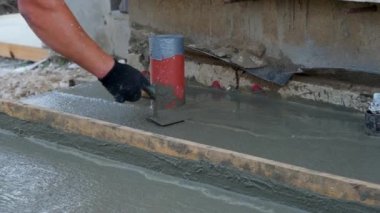 Uzun bir seviyelendirme aracı ile taze beton seviyelendiriliyor
