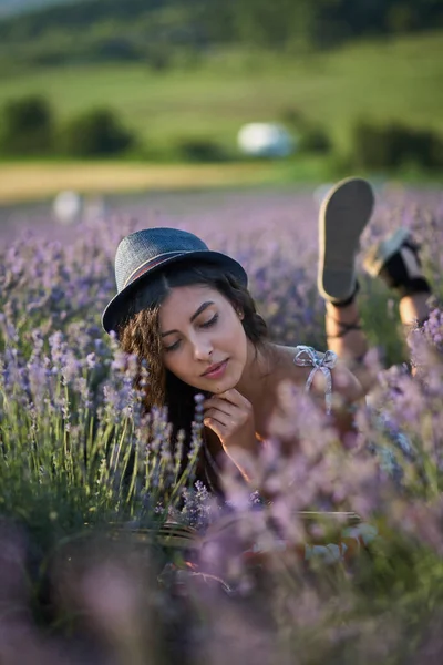 戴着帽子的年轻女子躺在薰衣草地里 — 图库照片