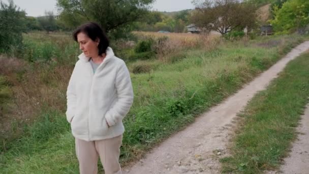 Jovens mulheres morenas caminha vagarosamente ao longo de uma estrada rural — Vídeo de Stock