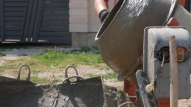Küçük inşaat alanındaki kum yığınının yanında eski kirli beton karıştırıcı. Evde küçük taşınabilir çimento karıştırma makinesi. İnşaat alanı