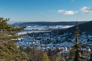 İzole edilmiş köy ve buzlu nehir içeren huzurlu kış manzarası, açık vadinin altındaki sakin karla kaplı bir köy.