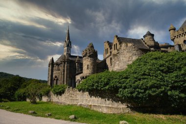 Kassel, Almanya - 15 08 2024. Fırtınalı gökyüzü ve yemyeşil yemyeşil bir zemine karşı nefis ve çarpıcı bir kale.