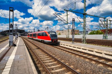 Modern train arriving at platform midday, dynamic commuter scene with clear motion lines, overhead wires