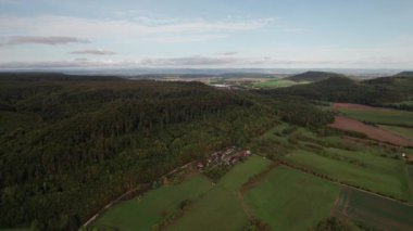 Güneşli Orman Tepeleri Canlı Yeşil Kanopi, Dağılmış Çiftlikler ve Virajlı Şeritler Temiz Mavi Gökyüzü ve Sıcak Gün Işığı Enerjik Sinema Ortamı Yaratıyor