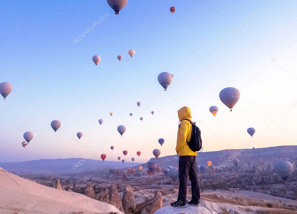 A tourist with a backpack sees on soaring hot air balloons in Cappadocia, Turkey, concept achievement, team, leader.