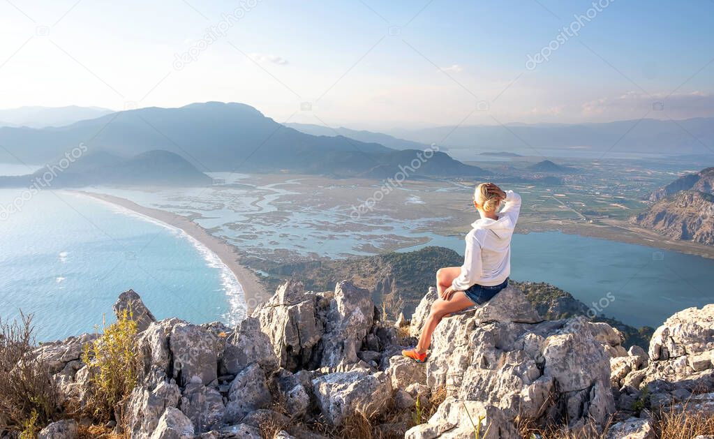 Young girl tourist looking at Iztuzu Beach and Dalyan panorama view from mountain