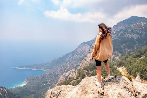 Chica joven en la cima de la montaña mira a la vista al mar —  Fotos de Stock