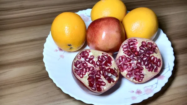 Granatapfel Und Orangefarbene Nahaufnahme Auf Teller Auf Holztisch — Stockfoto