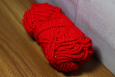 kırmızı renkli iplik, ahşap masada yakın plan.