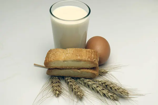 biscuit and ripe wheat and egg and milk on white background