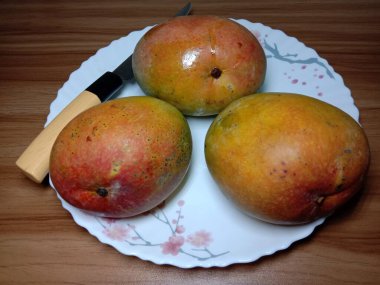 Olgun mango stoku ve tabağında bıçak var.