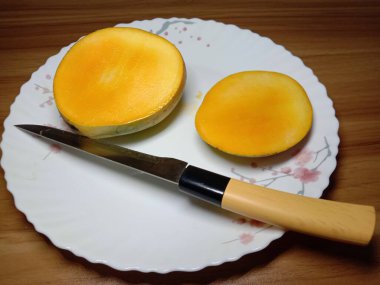 Olgun mango şeftalileri ve tabakta bıçak var.