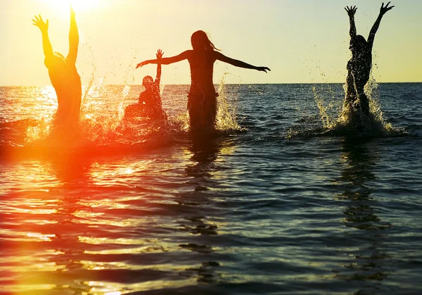 Silhouettes of people jumping in ocean