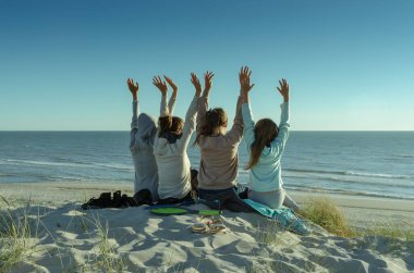 Genç kadınlar denizin kıyısındaki bir uçurumda oturuyor.