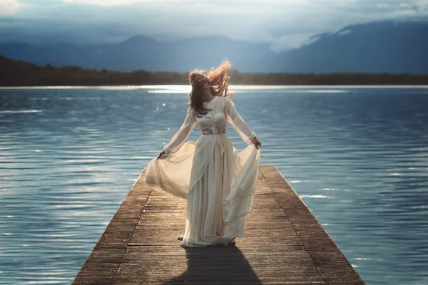 Young woman posing on lake pier — Stock Photo, Image