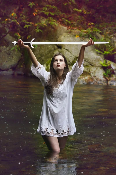 Beautiful woman lifting a sword to the sky — Stock Photo, Image