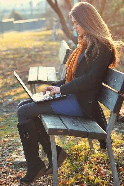 Beautiful girl works with laptop at the park — Stock Photo, Image