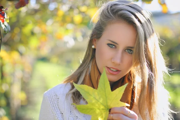 Beautiful young woman with autumn leaf — Stock Photo, Image