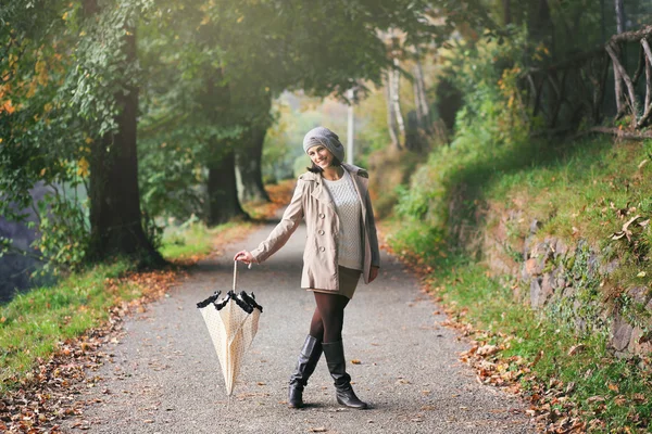 Beautiful woman with umbrella in a country road — Stock Photo, Image