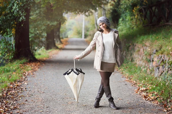 Beautiful woman posing with umbrella in a country road — Stock Photo, Image