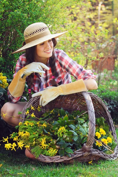 Красивый садовник позирует с плетеной корзиной, полной цветов — стоковое фото