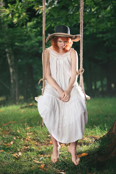 Red hair woman is thinking on a swing — Stockfoto
