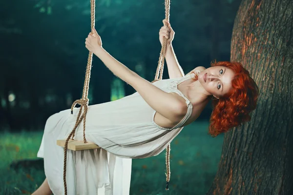 Beautiful woman on a swing in the forest — Stockfoto