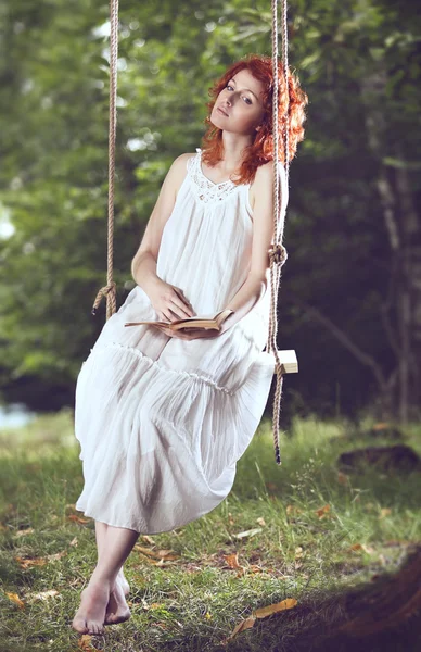 Schöne Frau mit roten Haaren auf einer Schaukel — Stockfoto