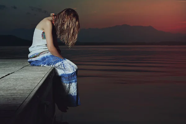 Одинокая женщина в печальном положении над водами озера — стоковое фото