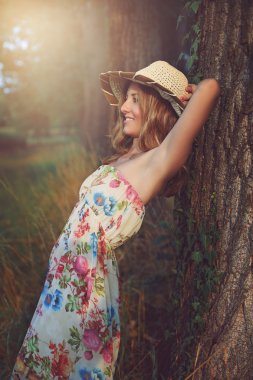 Bir ağaca yaslanmış güzel gülümseyen kadın