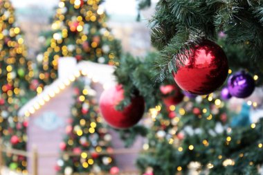 Evin arka planındaki köknar dallarında yılbaşı süslemeleri, şenlikli ışıklar, sokak aydınlatması. Kırmızı oyuncak topları olan Noel ağacı, şehirde bir tatilin büyüsü.