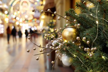 Alışveriş merkezinde süslemeli Noel ağacı. Yeni yıl oyuncakları, yürüyen insanlara ve festival ışıklarına odaklı olmayan bakış açısı.