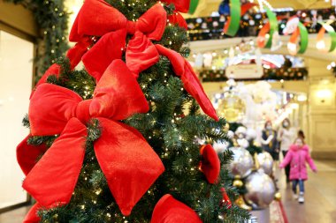 Alışveriş merkezinde kırmızı fiyonklu Noel ağacı. Yeni yıl süslemeleri, kış tatillerinde indirim.