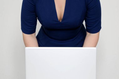 Dizüstü bilgisayarı üzerine eğilmiş mavi yakalı bir kadın. Seksi sekreter kavramı, ofiste kıyafet zorunluluğu