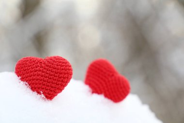 Sevgililer günü kalpleri kış ormanında, güneş ışığında. Karda iki kırmızı kalp, romantik aşkın sembolü, tatil için arka plan.