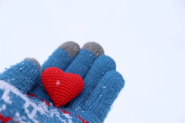 Avucunun içinde kar taneleri olan kırmızı bir kalp, kara karşı sıcak örülmüş bir eldiven. Romantik aşk kavramı, Sevgililer Günü ya da hayırseverlik.