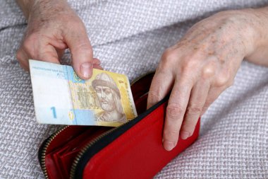 Yaşlı kadın cüzdanından Ukraynalı Hryvnia 'yı çıkarıyor. Ukrayna 'da emeklilik ödemeleri kavramı, emeklilikte tasarruflar, yoksulluk