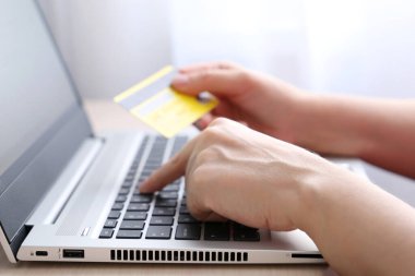 Laptop klavyesinde kredi kartı tutan kadın. Çevrimiçi alışveriş ve ödeme kavramı, mali işlemler