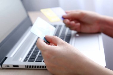 Dizüstü bilgisayardaki kredi kartları kadınların elinde. Çevrimiçi alışveriş ve ödeme kavramı, indirim, mali işlemler