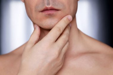 Tıraşlı çenesine, güzelliğine ve cilt bakımına dokunan adam. Erkek yüzü ve boynu yakın.