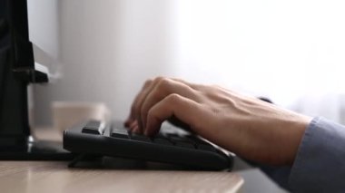 Erkek elleri gün ışığında klavyede. Yakından bakınca, adam çabucak metin yazıyor. Bilgisayarda ofis ya da ev işi kavramı