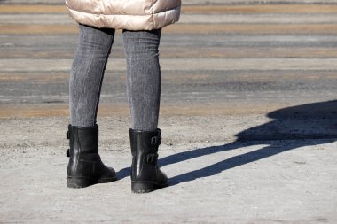 Kotlu ve çizmeli kız yaya geçidinin önünde duruyor. Şehirde yaya geçidi, sokak güvenliği, kadın bahar modası.