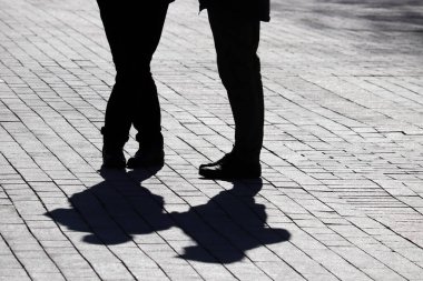 Sokakta siluetler ve gölgeler, yaya kaldırımında duran iki kişi. İlişki kavramı, şehir hayatı, dramatik hikayeler.