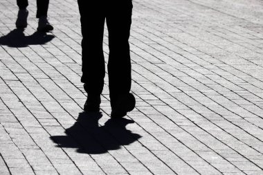 Siyah siluetler ve sokakta yürüyen insanların gölgeleri. Şehir hayatı kavramı, koronavirüs salgını sırasında karantinadaki sosyal mesafe.