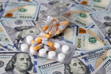 Şişedeki haplar ve kapsüller Amerikan dolarları üzerinde. ABD 'de sağlık hizmeti kavramı, ilaç ticareti, uyuşturucu fiyatları, eczane, tıp ve ekonomi